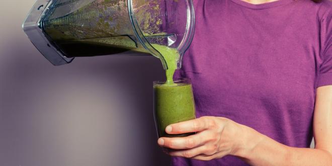 A woman pouring a kale and spinach smoothie