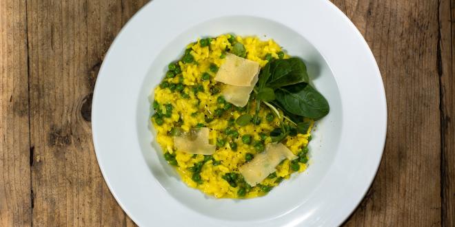 A bowl of leek and pea risotto with garnish and cheese